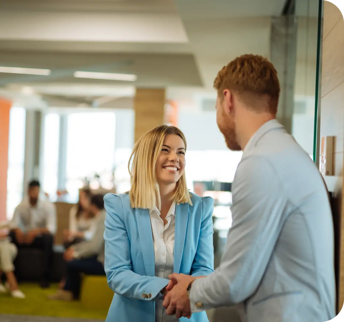 Two colleagues shaking hands in a modern office, representing company values