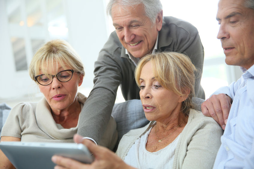 group of retired people sitting in sofa and using tablet