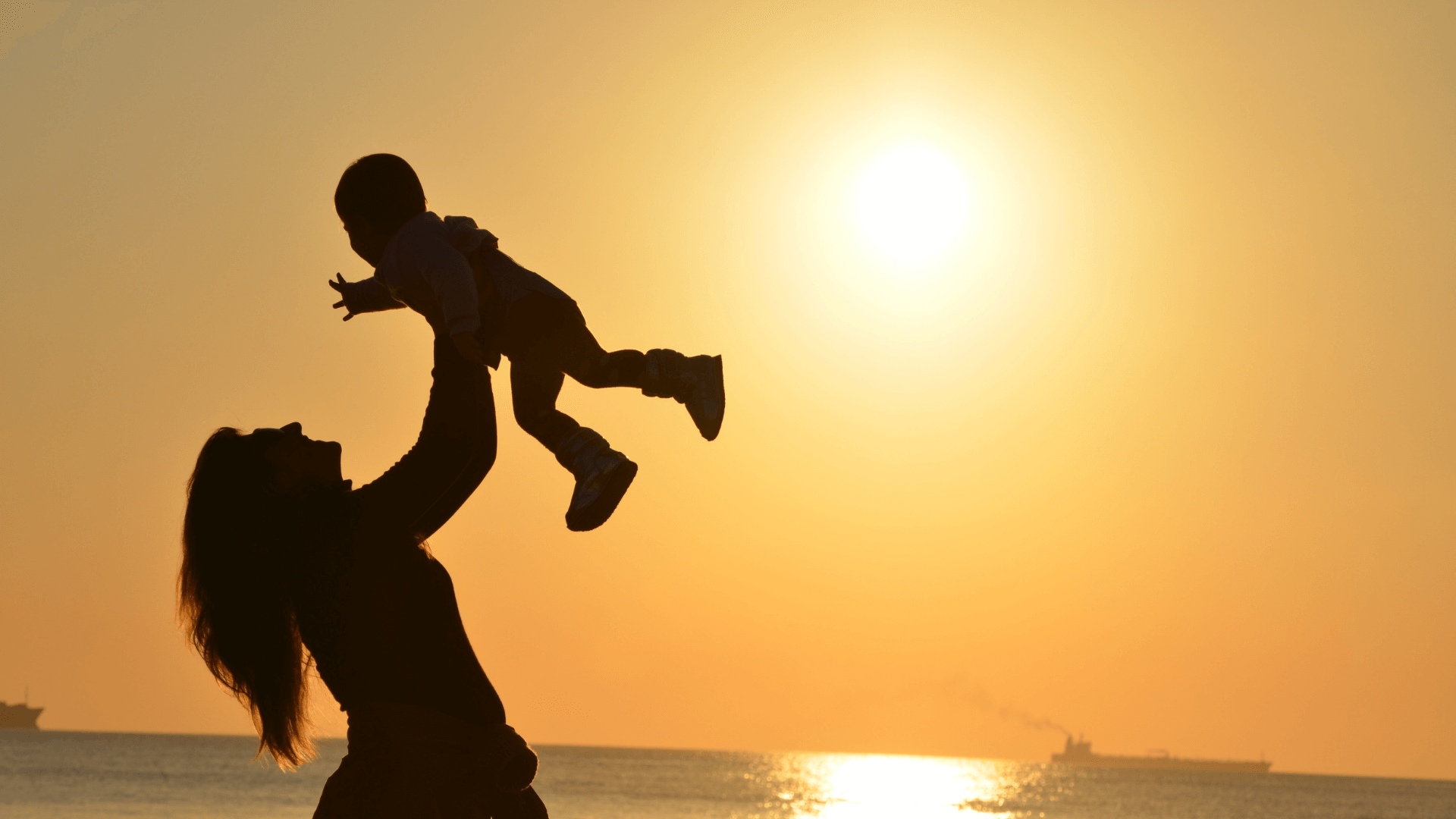 An image of a silhouette of a mother holding her child with a sunset in the background. life insurance for children