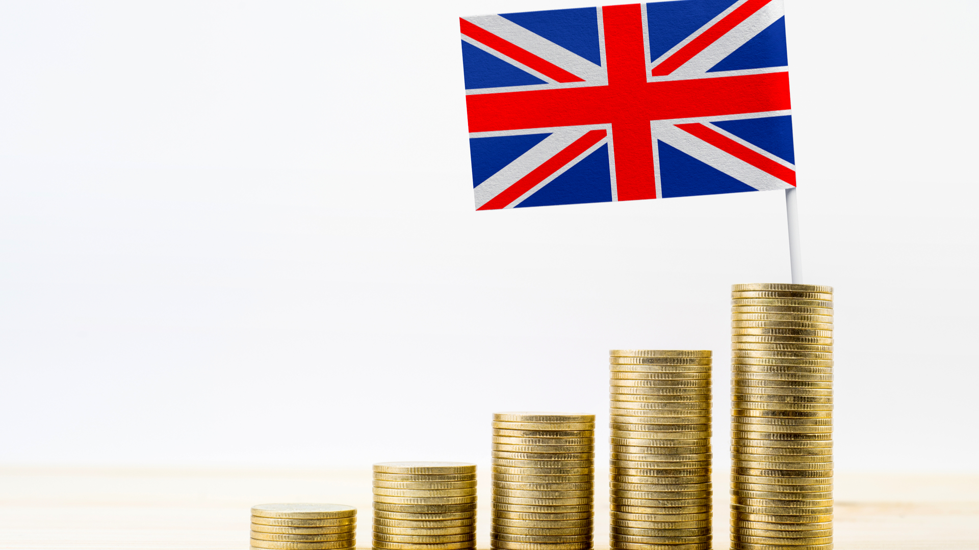 An image of 5 stacks of coins looking like steps. The last step has a Union Jack flag on top of it. National Insurance when living abroad