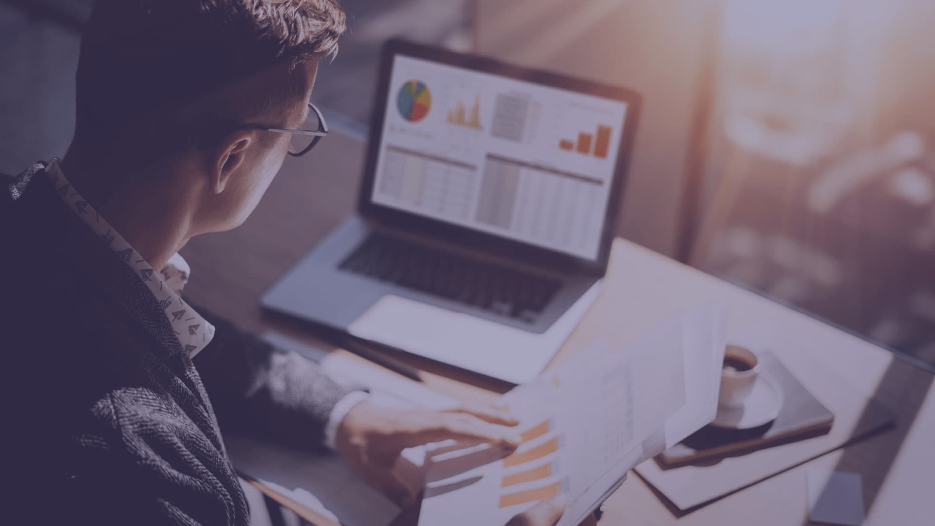 An image of a man looking at charts on the laptop and comparing them with the charts on a piece of paper. How to build a financial plan in 4 steps