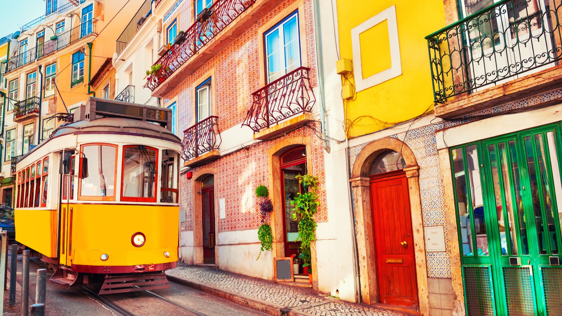 An image of a Portuguese city with vibrant colours and a yellow tram on the left. Guide to NHR in Portugal