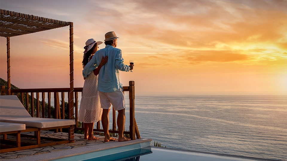 Retirement for couples, A romantic couple on summer vacation enjoys the sunset over the Mediterranean sea by the pool with a glass of Aperitif